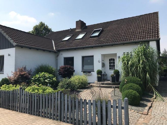 Ein gemütliches Einfamilienhaus mit gepflegtem Garten und Holzzaun.
