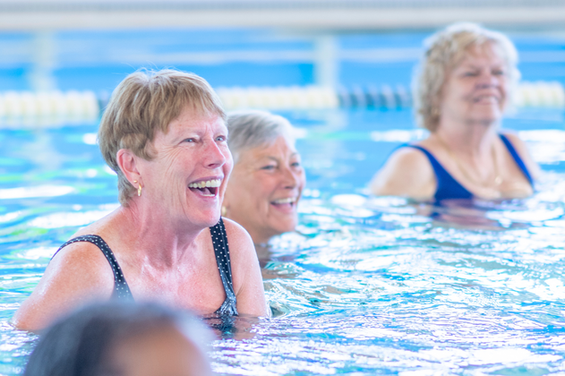 Ältere Damen beim Aquafitness im Schwimmbecken beim Lachen. 