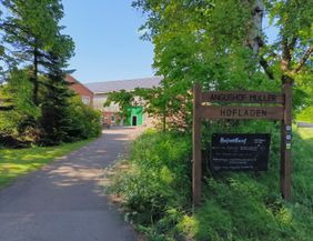 Willkommensschild und Hofauffahrt des Betriebes