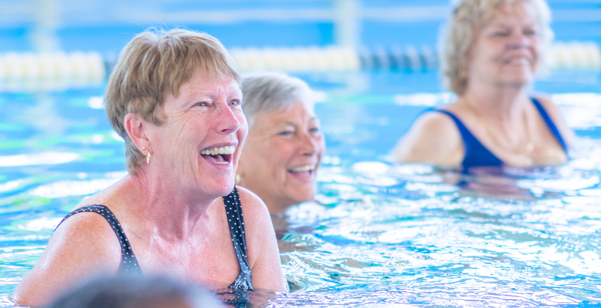 Ältere Damen beim Aquafitness im Schwimmbecken beim Lachen. 