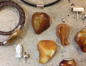 A collection of jewelry made from amber, including earrings, pendants, and a bracelet. The jewelry pieces come in various shapes and are designed in warm earth tones.
