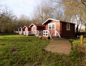Rote Übernachtungshütten stehen auf einer grünen Wiese