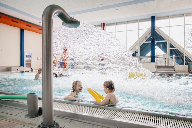 2 Kinder unter einem Nackenschwaller im Schwimmbad