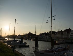 Boote im Hafen bei Sonnenuntergang mit historischen Gebäuden im Hintergrund.