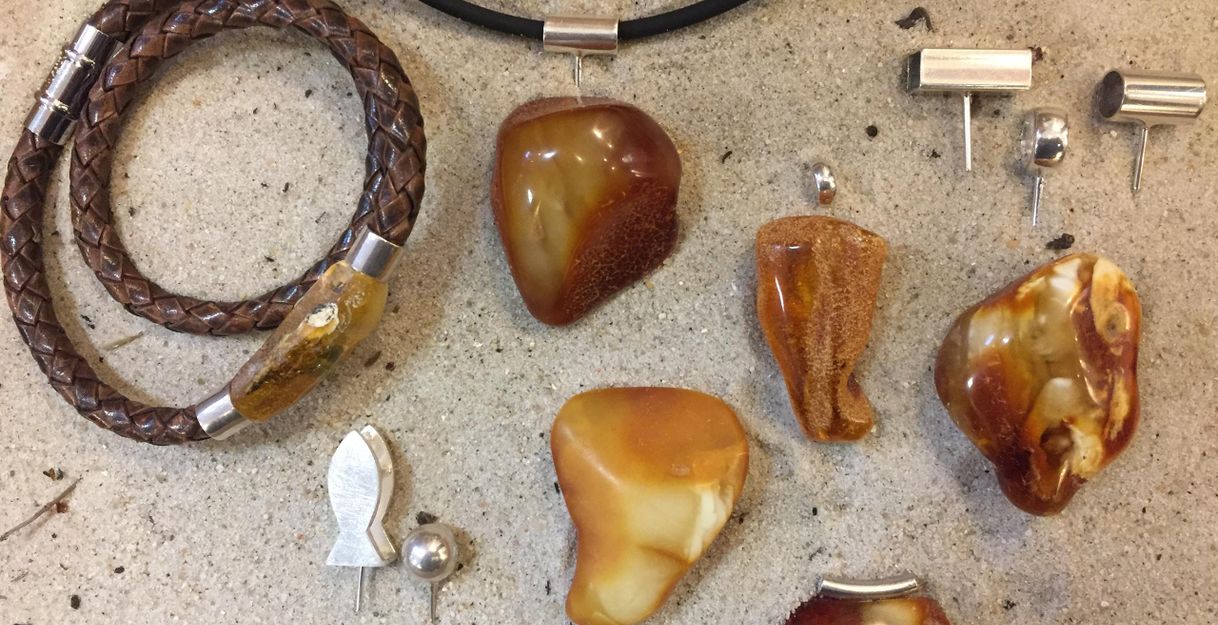 A collection of jewelry made from amber, including earrings, pendants, and a bracelet. The jewelry pieces come in various shapes and are designed in warm earth tones.