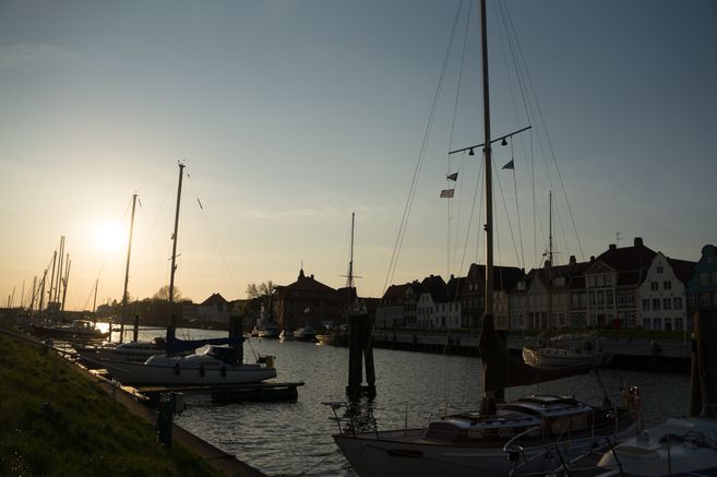 Boote im Hafen bei Sonnenuntergang mit historischen Gebäuden im Hintergrund.