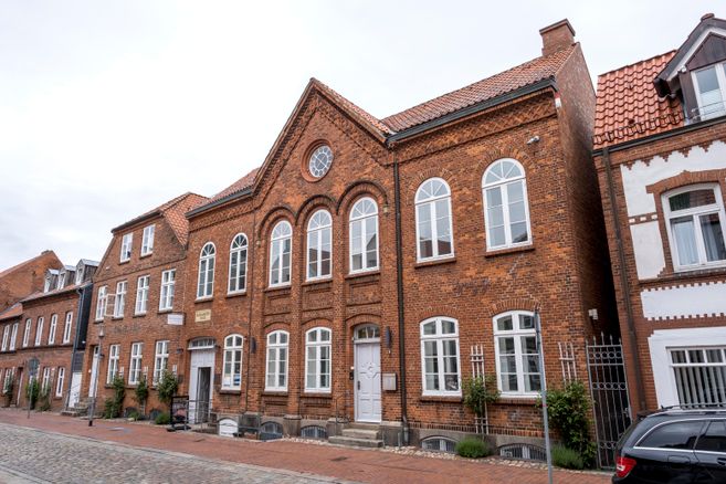 Backsteingebäude mit weißen Fenstern und einem Schild, das auf ein Museum hinweist.