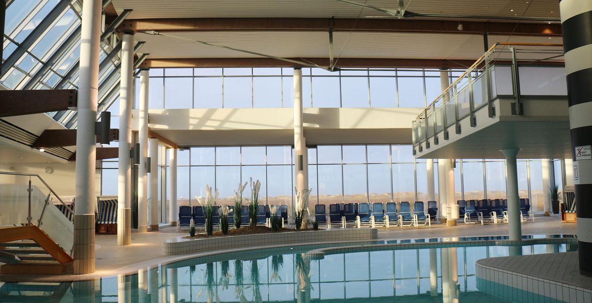 Ein modernes Schwimmbad mit großen Fenstern und viel natürlichem Licht. Die Umgebung ist einladend und bietet Ruhe für die Gäste.