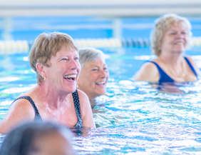 Ältere Damen beim Aquafitness im Schwimmbecken beim Lachen. 