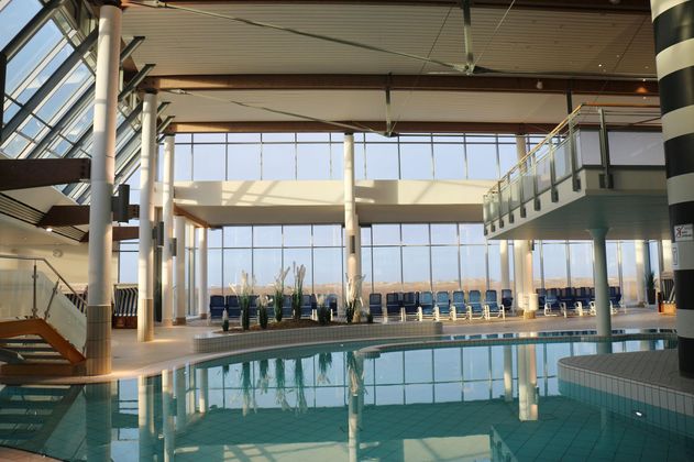 Ein modernes Schwimmbad mit großen Fenstern und viel natürlichem Licht. Die Umgebung ist einladend und bietet Ruhe für die Gäste.