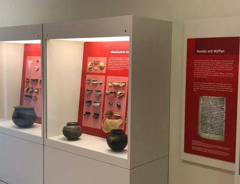 Ausstellungsstücke in Vitrinen mit rotem Hintergrund 