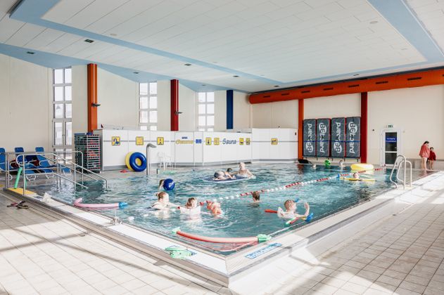 Ein Schwimmbecken mit spielenden Menschen und Spielzeug im Wasser