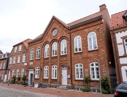 Backsteingebäude mit weißen Fenstern und einem Schild, das auf ein Museum hinweist.