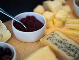 Nahaufnahme einer Käseplatte mit verschiedenen Käsesorten und einer Schale Chutney.