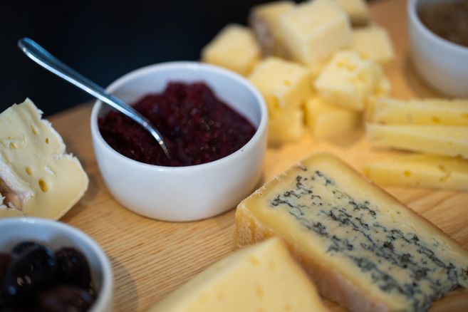Nahaufnahme einer Käseplatte mit verschiedenen Käsesorten und einer Schale Chutney.
