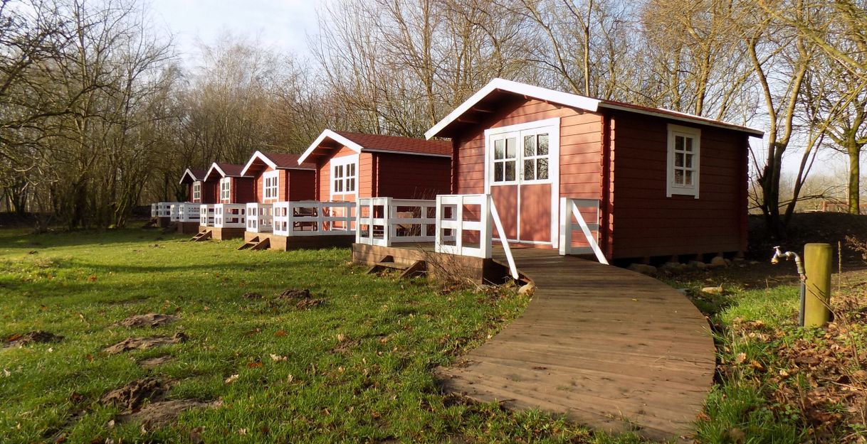 Rote Übernachtungshütten stehen auf einer grünen Wiese